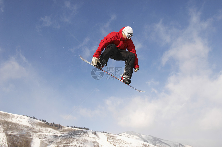 年轻男性滑雪运动员在云天上跳跃的低角度视图图片
