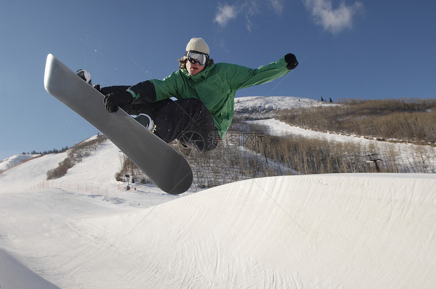 在雪山上表演特技的全身年轻滑雪运动员图片