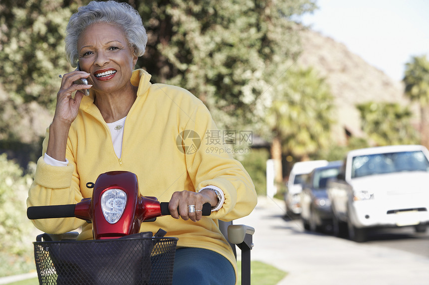 一名非洲裔美国高龄妇女坐在摩托车上时使用手机的肖像 当时她坐在摩托车上图片