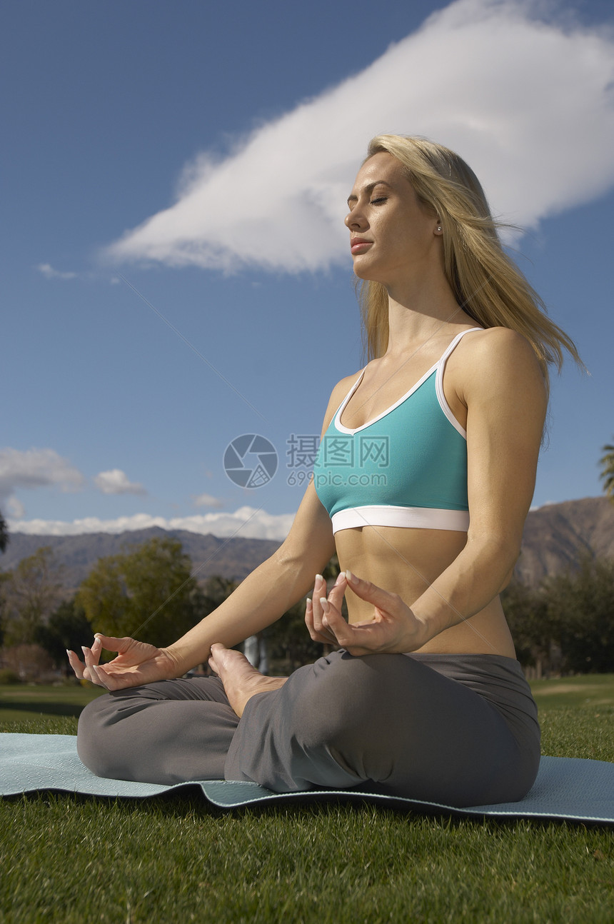 年轻女性在公园露珠姿势上练瑜伽图片