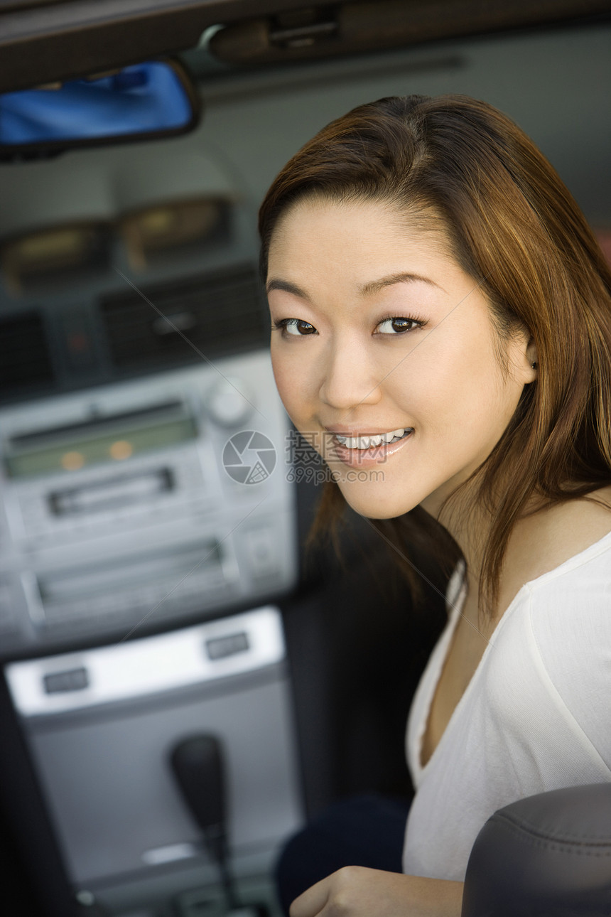 一位美丽的年轻韩国女子在车里微笑的肖像图片