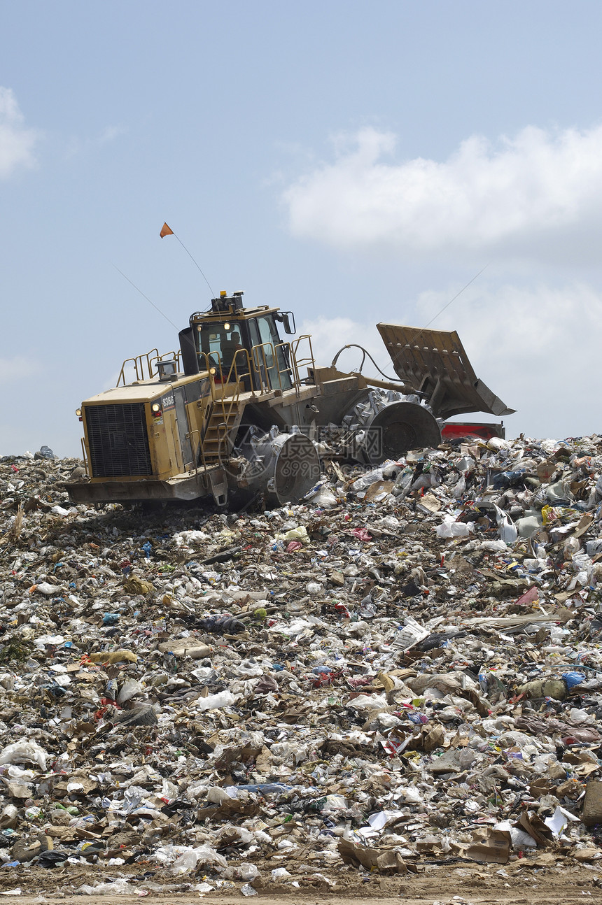 在垃圾倾倒场搬运垃圾的挖土机环境问题环境倾销挖掘机运输填埋场图片