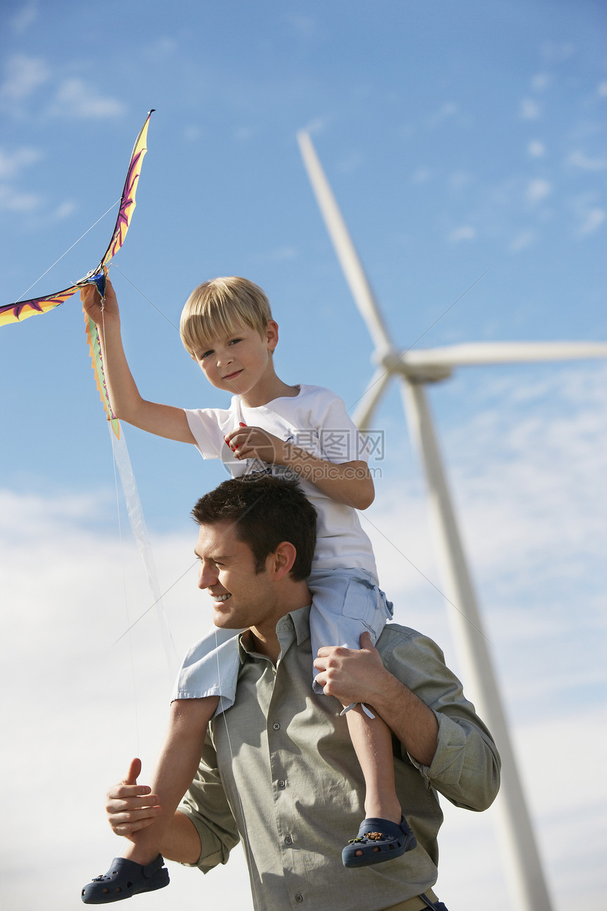 在风力农场 父亲肩上坐着风筝的小男孩图片