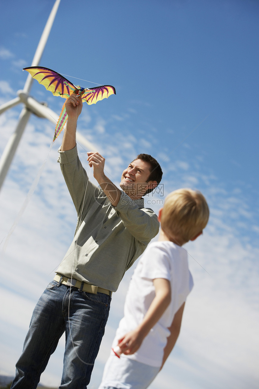父亲和儿子在风力农场玩龙风筝图片