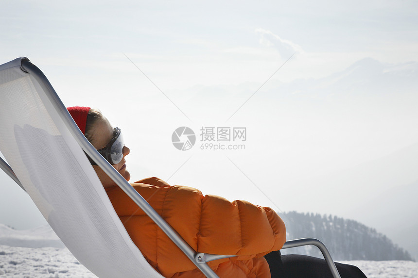 在雪中坐在草椅上的人滑雪者躺椅地平线一人服装胜地滑雪风景丘陵太阳镜图片