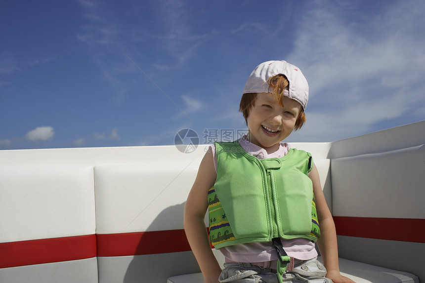 坐在游艇上穿着救生衣的快乐可爱男孩的肖像图片