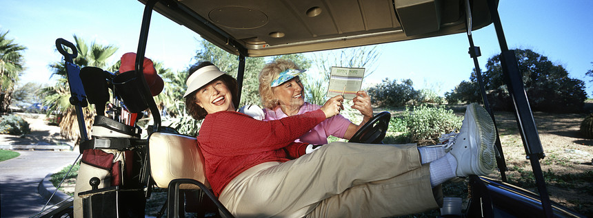 两个高级妇女在高尔夫车里大笑图片