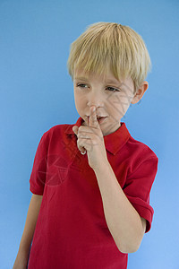 小可爱男孩 用手指在嘴唇上 隔着蓝色背景高清图片