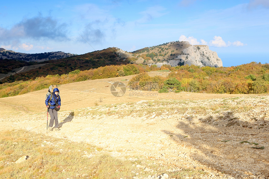 带背包的旅游客去山上女士天空活动游客蓝色岩石爬坡旅行女性远足者图片