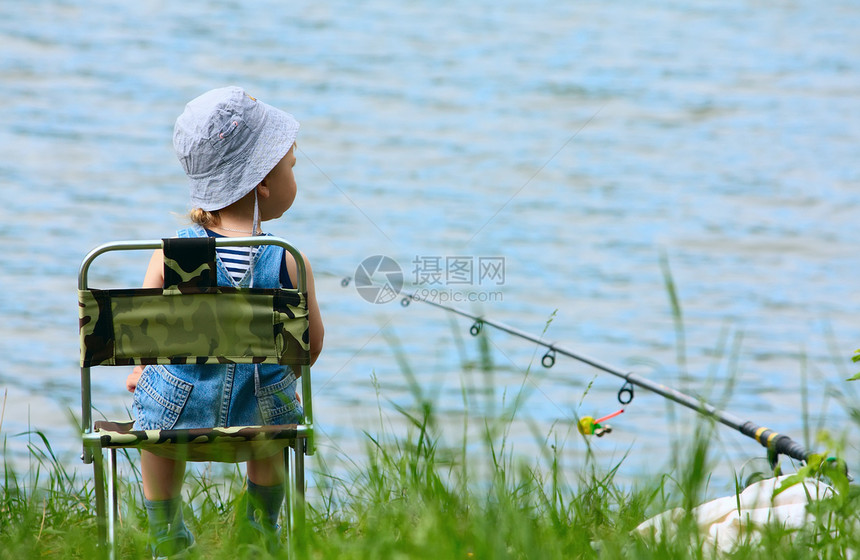 有钓鱼棒的小男孩蓝色童年孩子绿色血管钓鱼爱好季节海滩活动图片