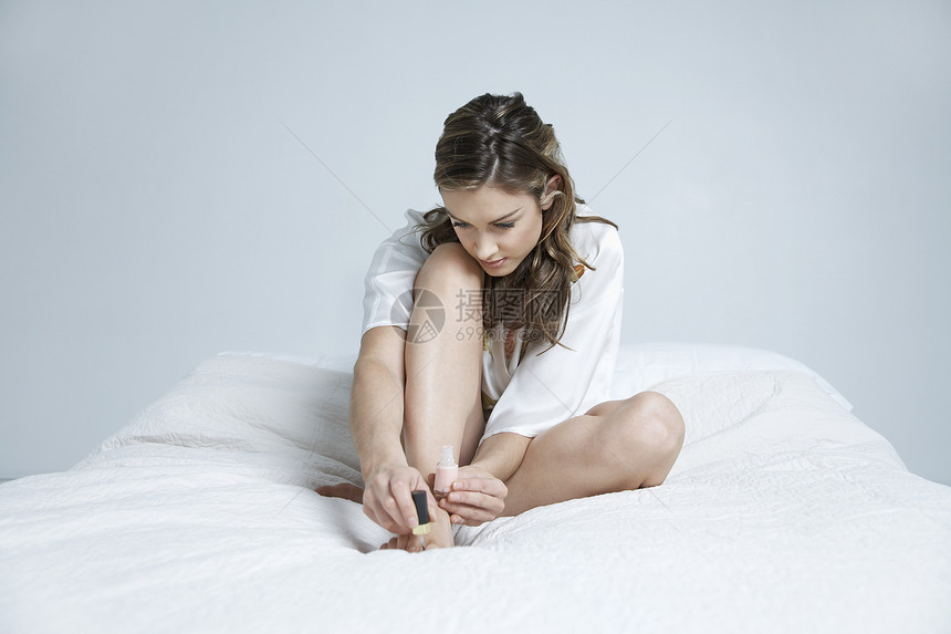 床上的年轻女子油漆脚指甲图片