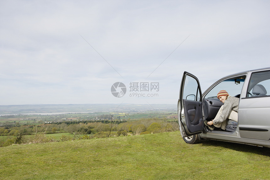 年轻女性登山女徒步者坐在汽车里时绑鞋的侧视角图片
