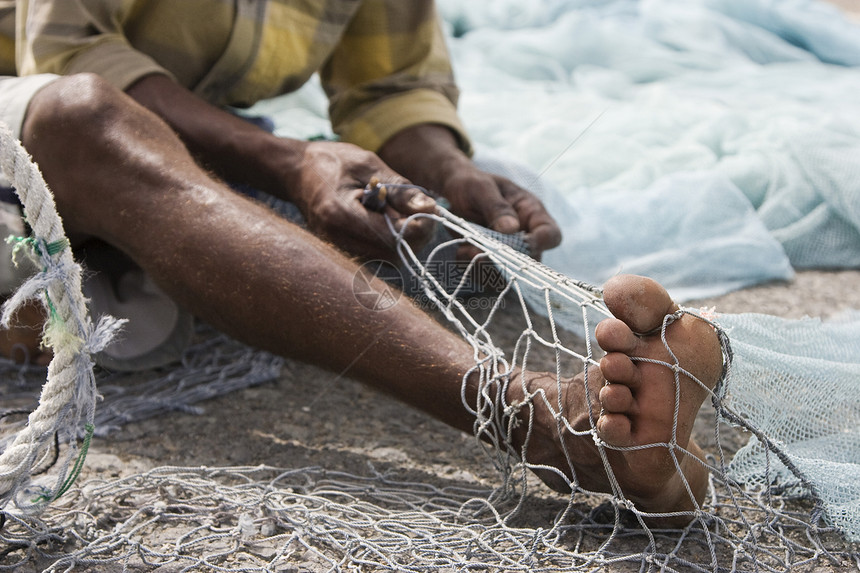 当地渔民修补他在Fujairah网中的洞和绳子方式渔业男人渔夫修复裁剪特写生活视图图片