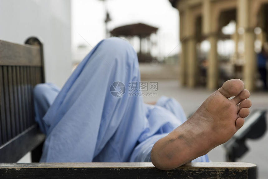 迪拜UAE男子在迪拜Bur的木板路边的公园长凳上休息图片