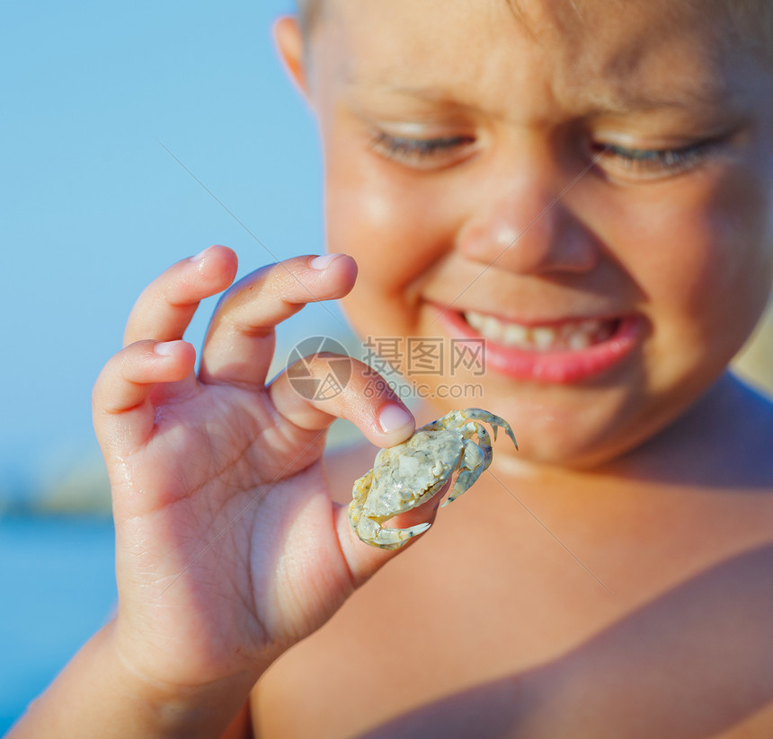 男孩抱螃蟹蓝色旅行喜悦婴儿男生孩子男性海岸晴天情感图片