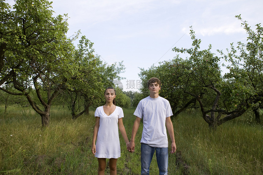 在果园中握手的年轻夫妇团结成年服装风光夫妻两个人个人生长休闲树木图片