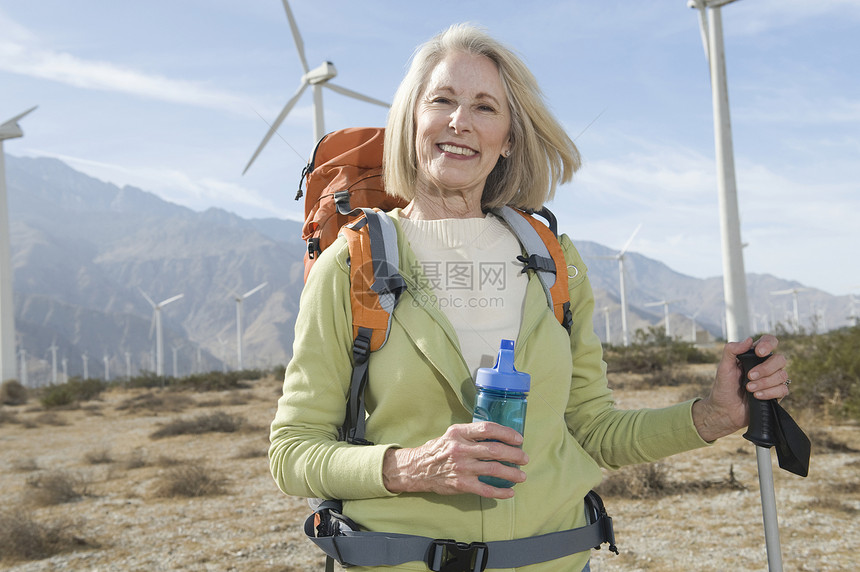 在风力农场附近带背背背背包的老年妇女生态旅游活动能源环境问题运动衫服装环保上衣远足闲暇图片