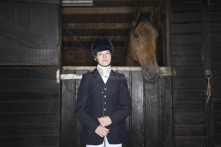 骑马的女性骑马手的肖像 马匹稳定鞭子女孩动物友谊工作骑马帽夹克团结水平木头图片
