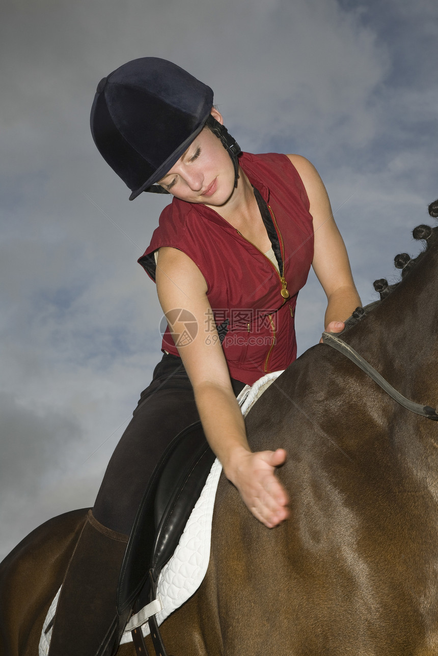 抚摸马的女性骑马者图片