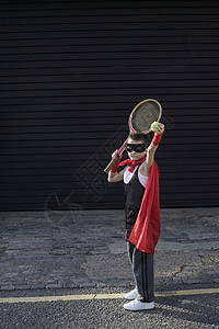 男孩穿着佐罗服和网球拍打背景图片