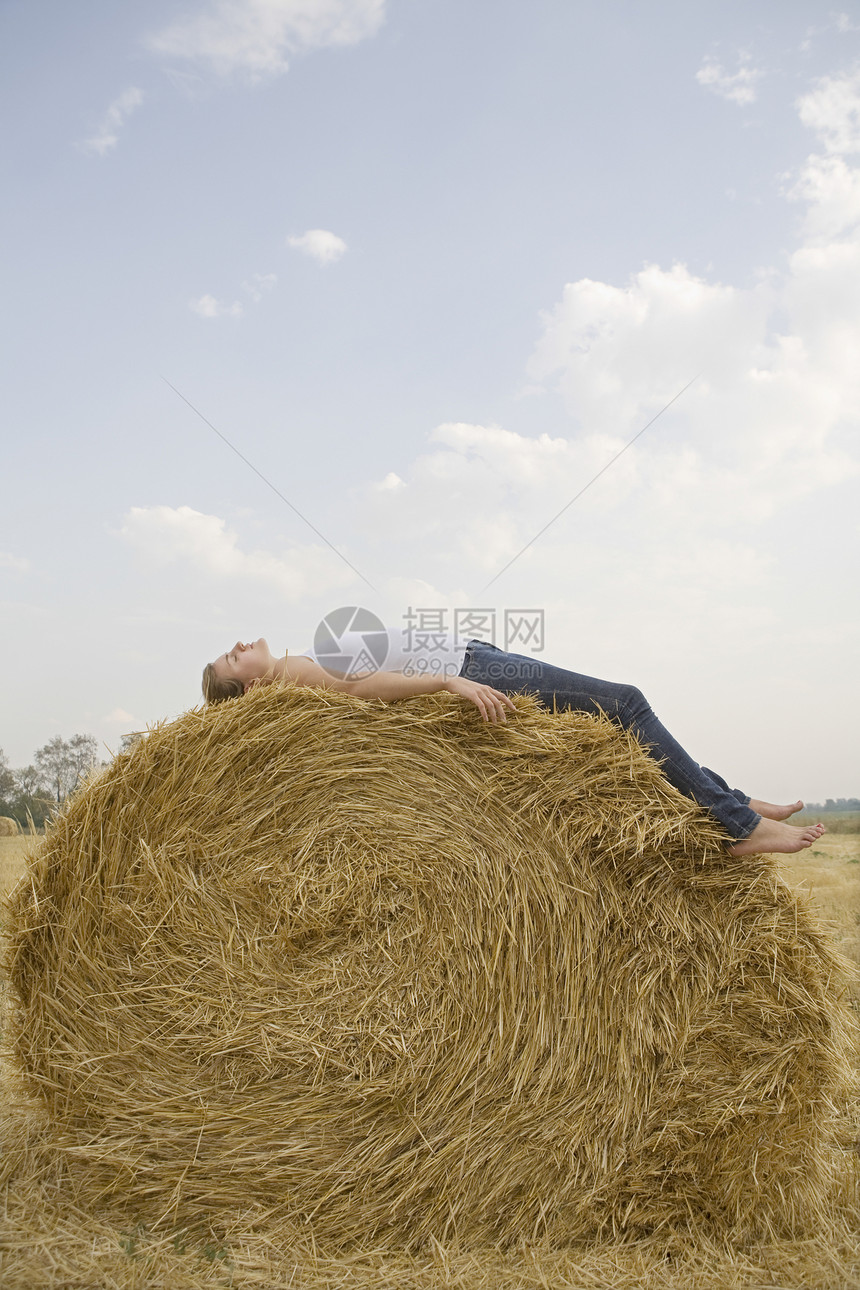 田里休息在干草泥巴上的年轻女子图片