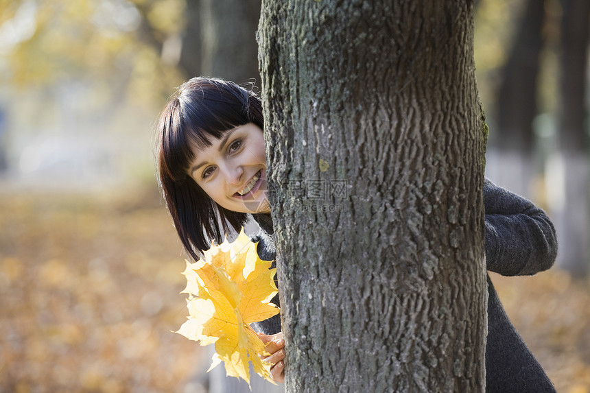 女子在公园里把树后面的树叶放在树后面图片