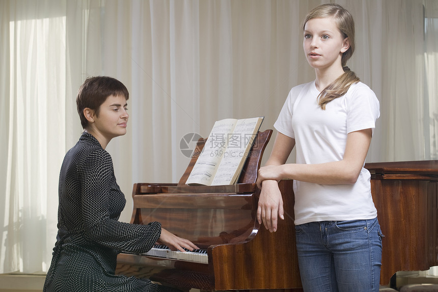 女孩(13至15岁)在教师的陪同下唱歌 弹钢琴图片