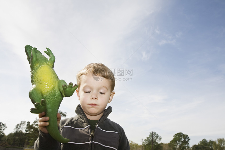 带着玩具恐龙的不高兴男孩图片