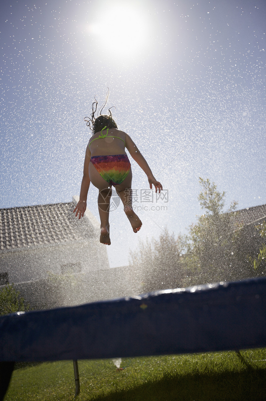 南非开普敦女孩跳跃在蹦床线上低角度乐趣阳光泳衣连体休闲喷雾运动青年活力图片