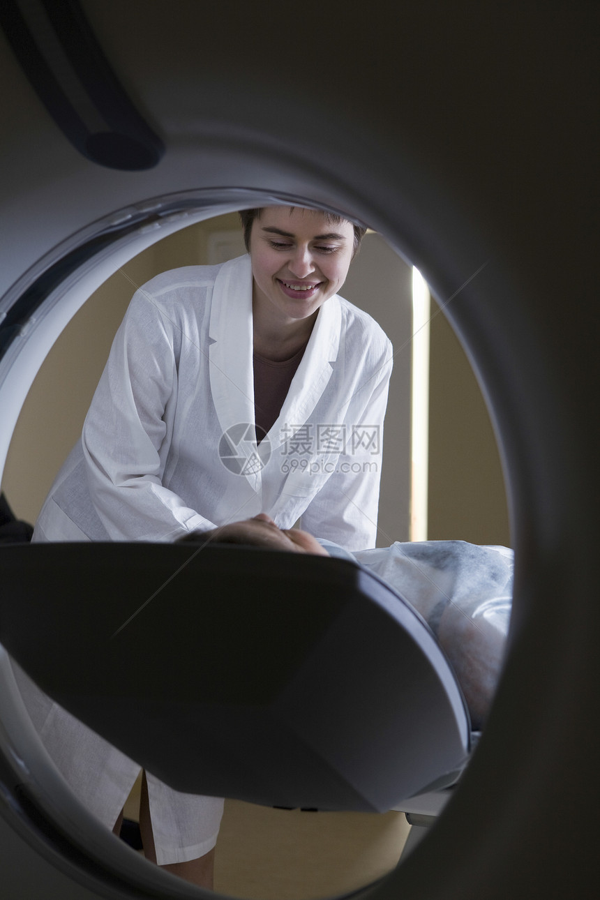 妇女躺在CAT扫描机前的妇女微笑专注技术医生医疗医学大衣考试个人享受图片