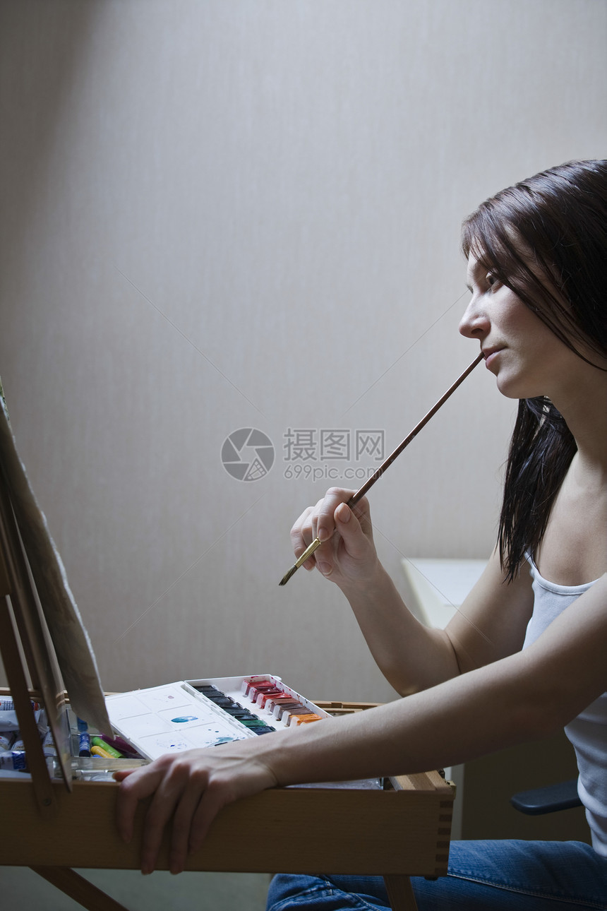 女人坐在地架前 拿着油漆刷子图片