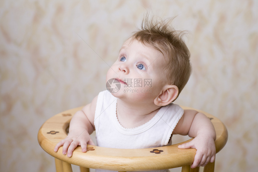 婴儿男孩坐在高椅子上 抬起头来图片