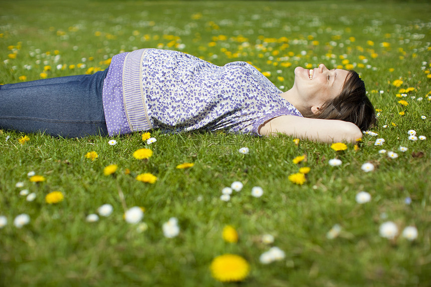 躺在草地上的孕妇长发休闲女士眼睛公共公园野花服装微笑头发女子图片