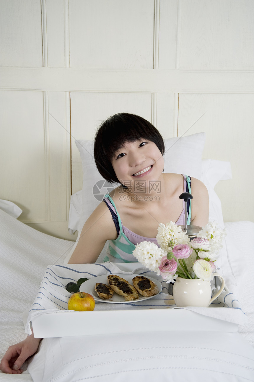 年轻女性在床上吃早餐图片