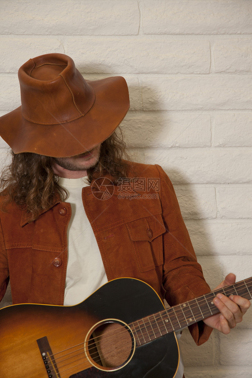 身戴牛仔帽和弹吉他的中成年男子图片