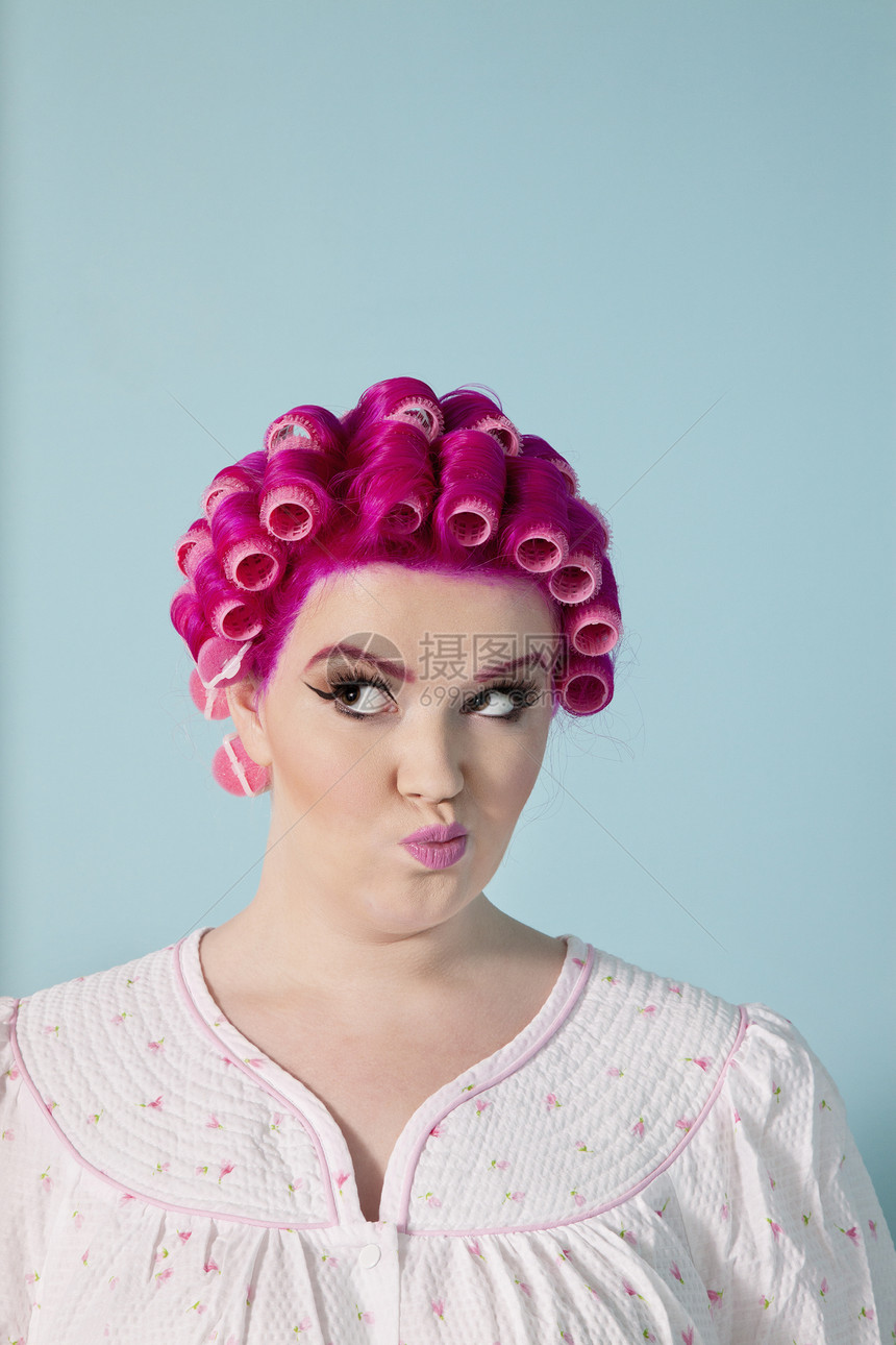 年轻女性用粉红头发和卷发做脸孔 以彩色背景制作图片