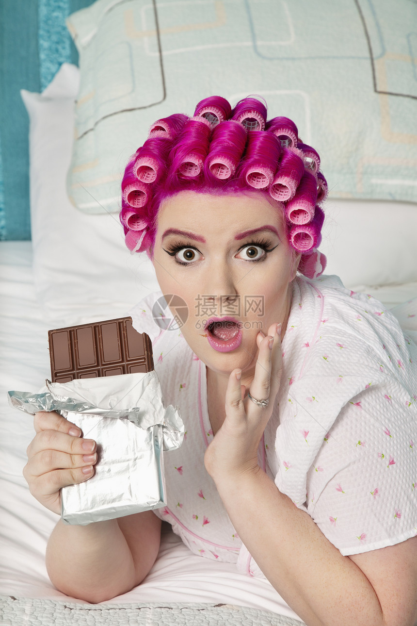 在床上躺着巧克力的震惊女人的肖像图片