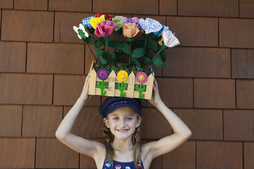 小女孩头顶用木箱装人造花朵的肖像图片