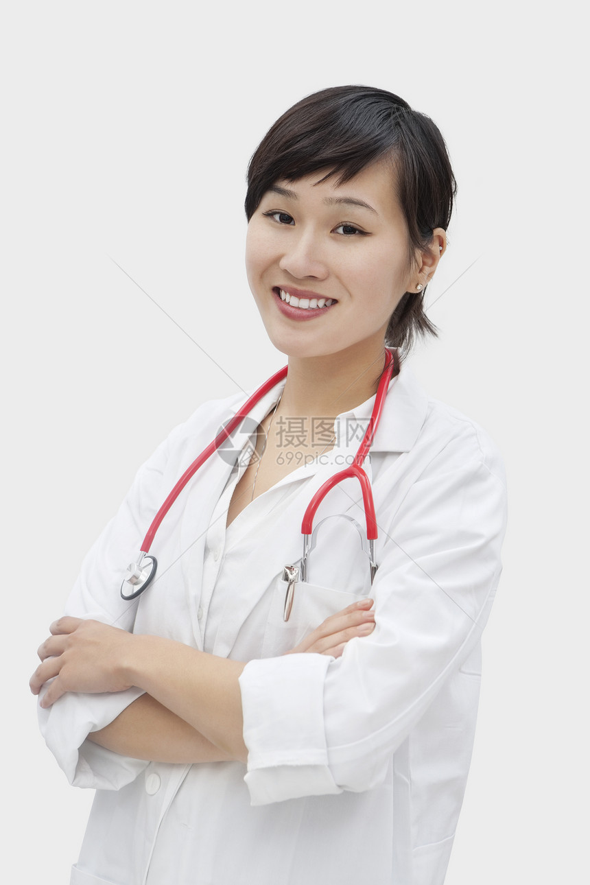 一个亚洲女兽医站立的手臂穿过灰色背景的纵向肖像图片