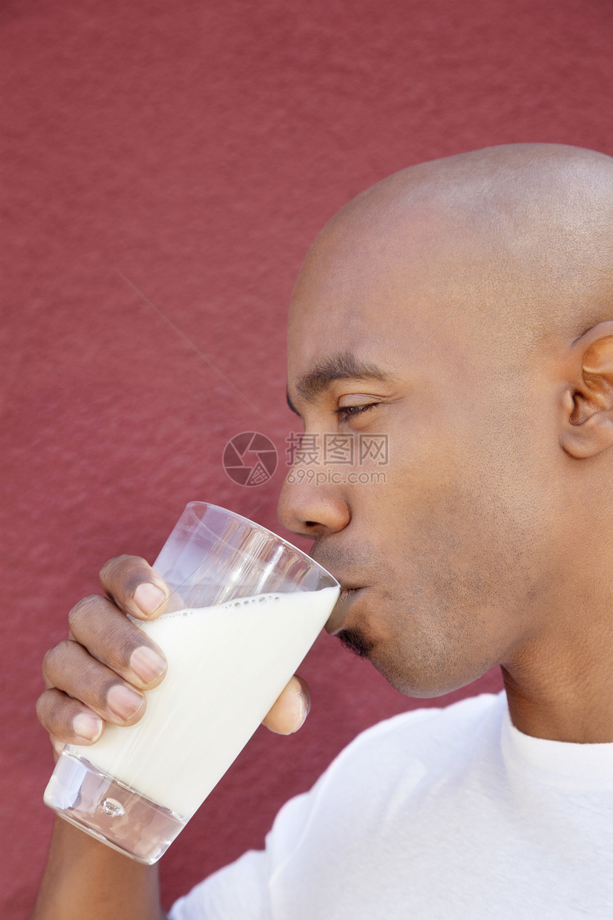 一个非洲裔美国人在彩色背景上 喝牛奶的侧面观图片