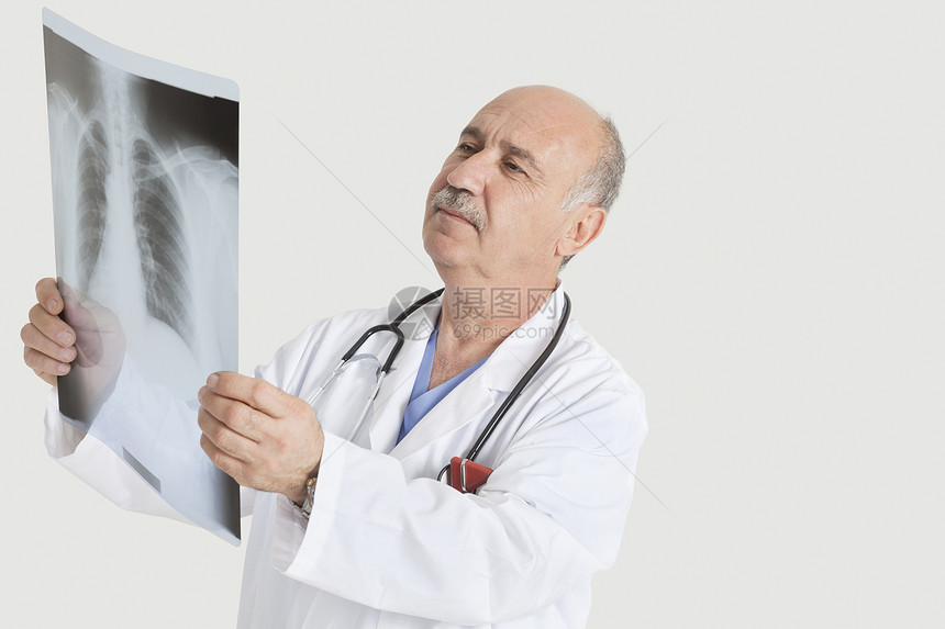 高级男医生 检查灰色背景的医用射线男性影棚器材男士成人白大褂x射线工作服秃顶彩色图片