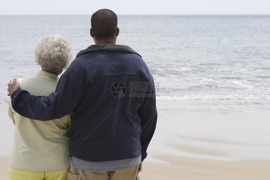 男人用手臂围着一个女人 在水边的边缘孩子安慰海滩母亲夫妻团结儿子沉思年龄悲伤图片