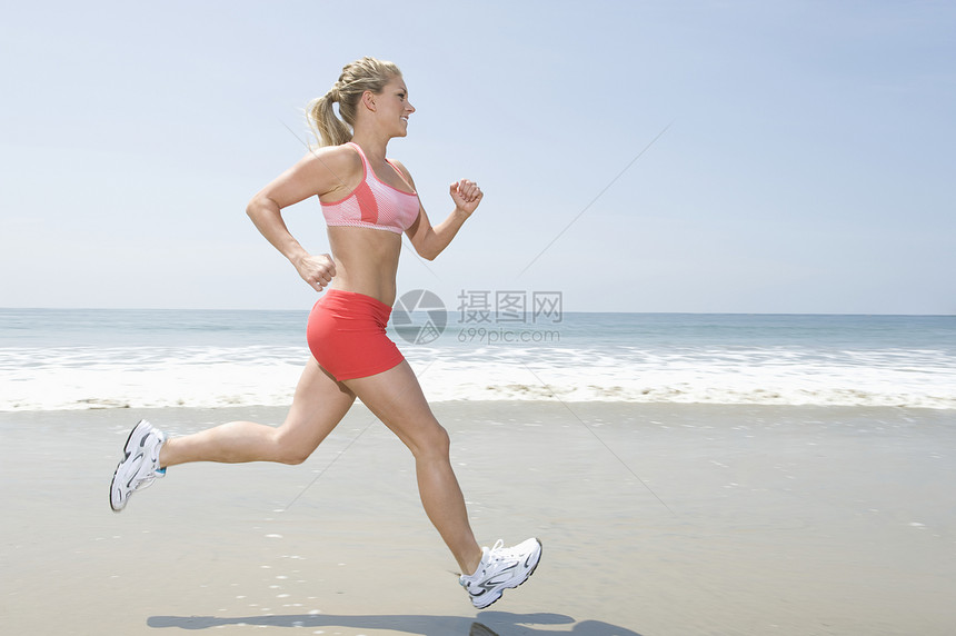 女人在海滩上慢跑跑步娱乐冲浪热裤运动海洋文胸头发锻炼长发图片