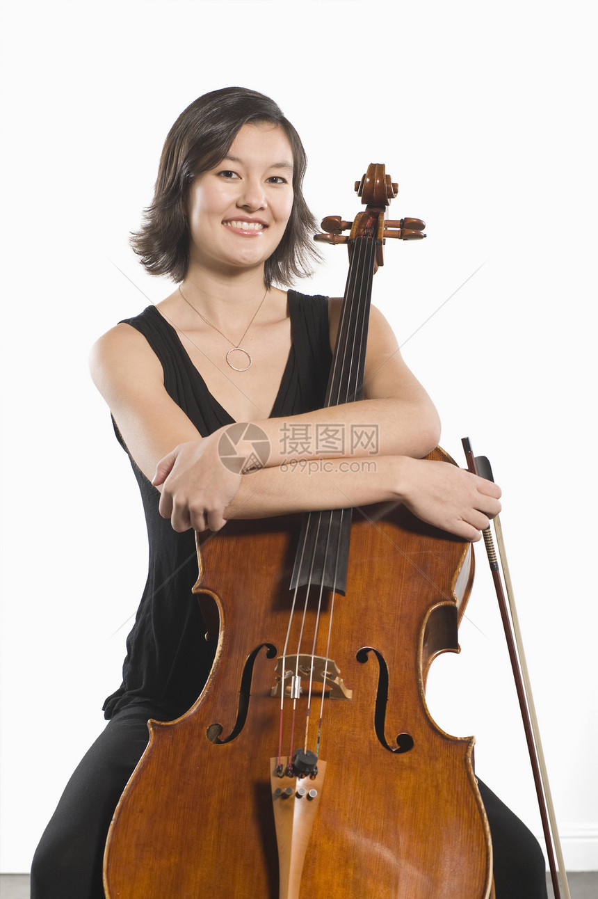 一个快乐的女大提琴手的肖像 与双臂折叠在大提琴之间图片
