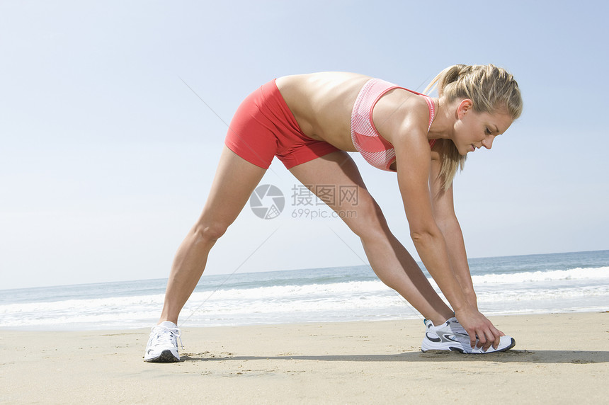 妇女在海滩上运动健康外表头发娱乐热裤运动装拉伸金发红色海洋图片