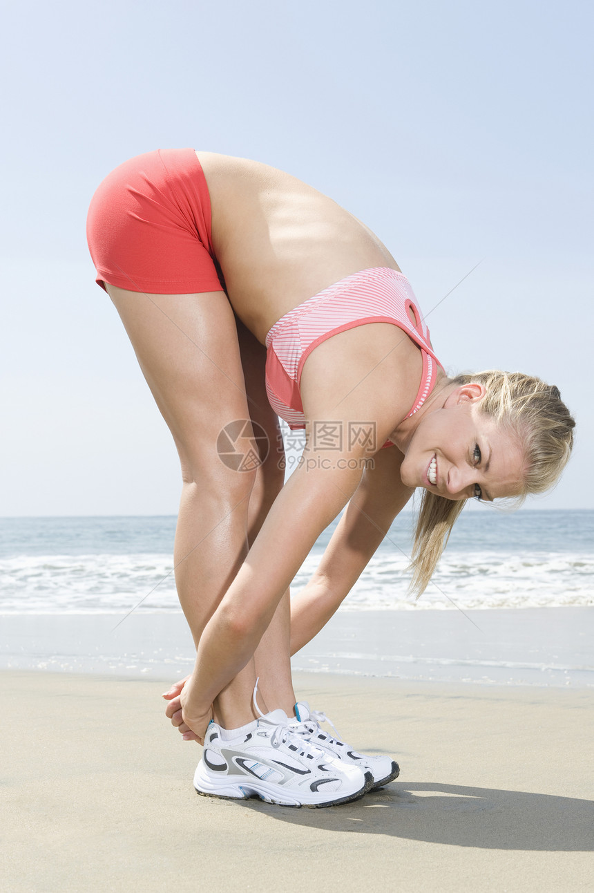 妇女在海滩上运动热身健康文胸拉伸头发微笑长发海洋热裤灵活性图片