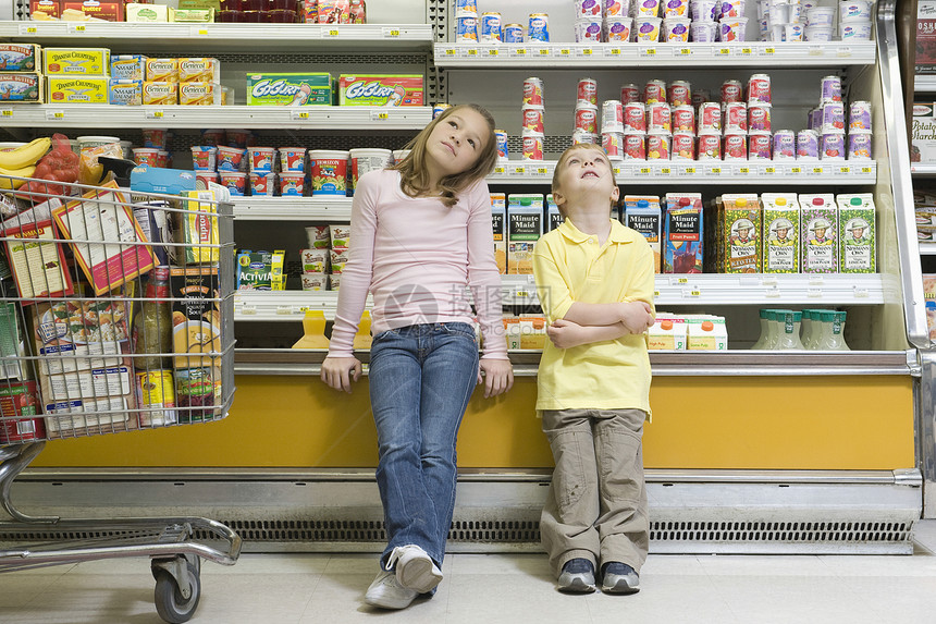 在超市冰箱柜台旁边坐着的 哥哥姐姐和妹妹图片