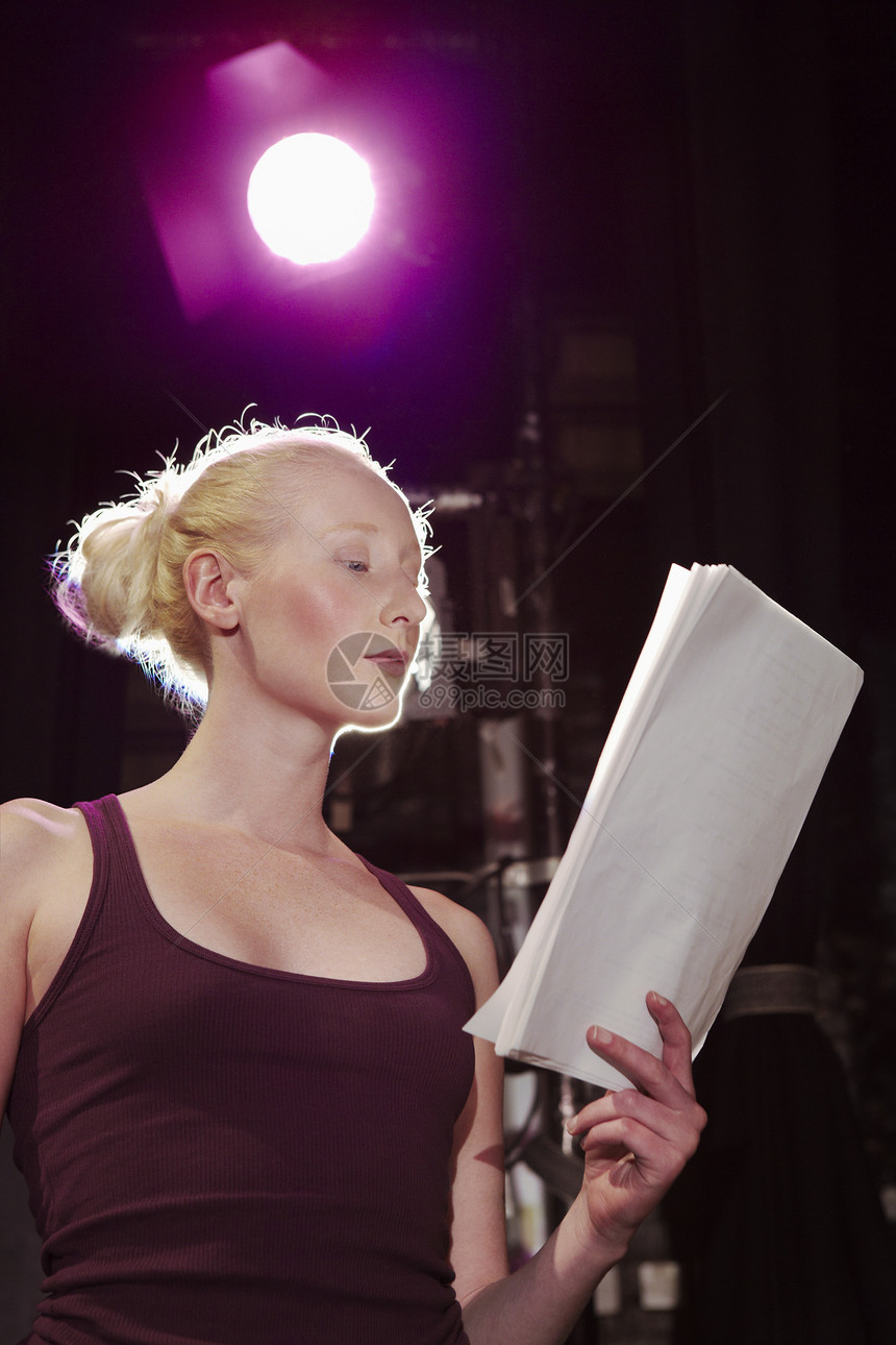 一名年轻妇女在舞台上阅读脚本的低角度视角图片