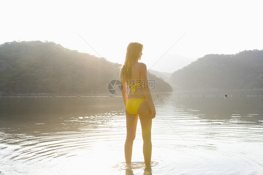 黄色比基尼妇女站在湖边活动游泳林地休闲游泳衣码头同心水面女子女士图片