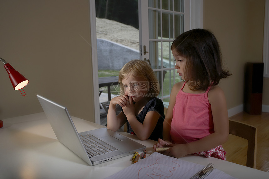 女孩使用计算机姐姐专注两个人沟通外表棕色电脑孩子们头肩头发图片
